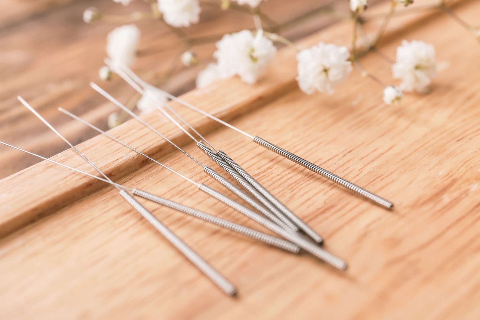 A closeup stand with acupuncture needles on wooden background.