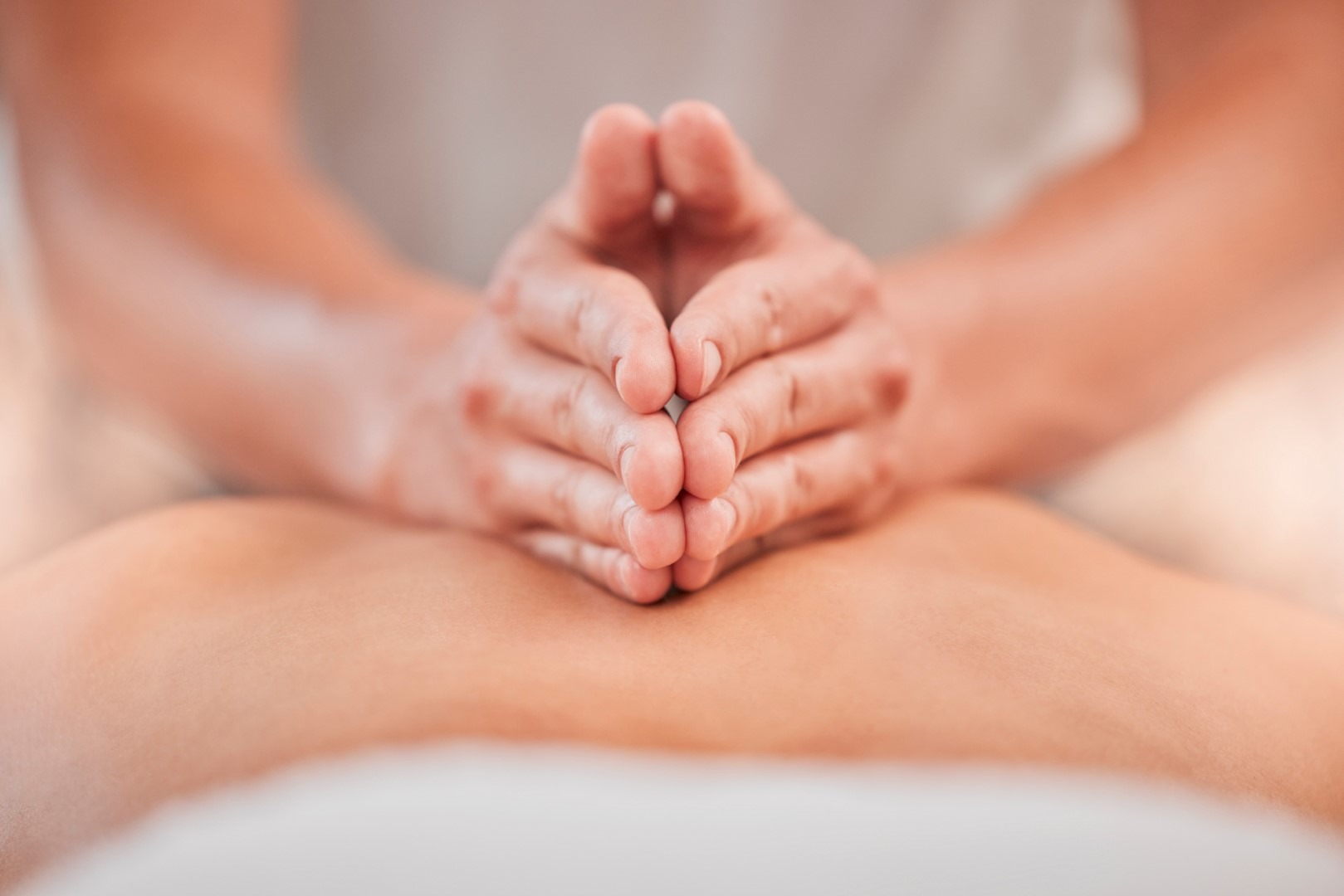 Close up of two hands cupped together massaging a person's back.