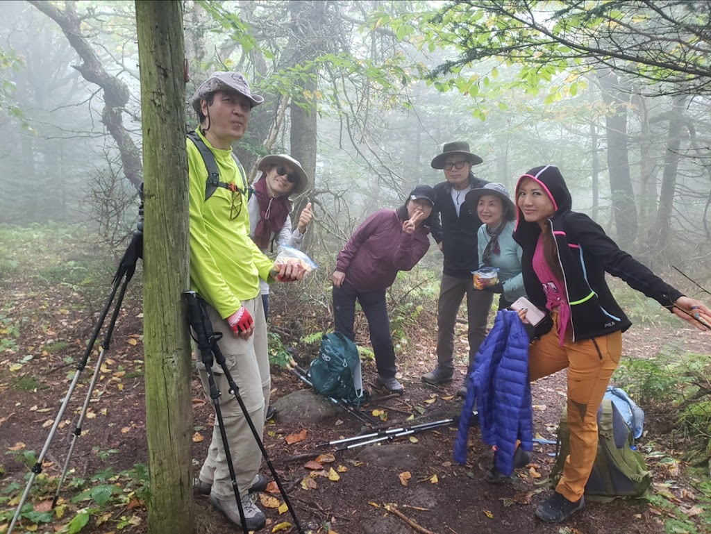 6 adults in a foggy forest wearing warm clothes.